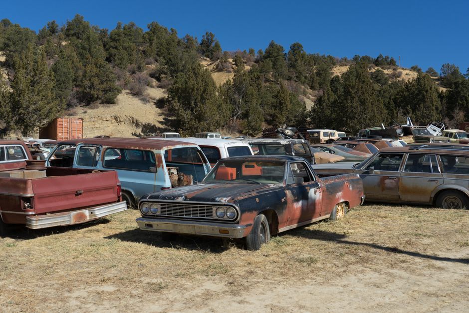 Rusted old vehicles sitting in an outdoor scrapyard.