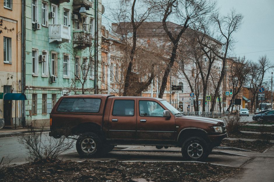 A vintage pickup truck parked on a quiet urban street lined with historic buildings.