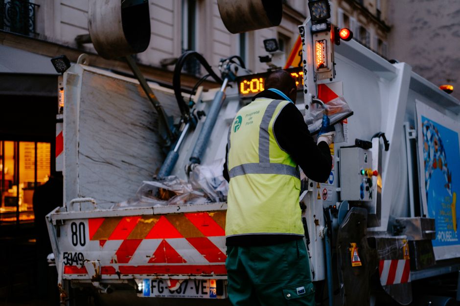 Waste collector loading a collection truck on a street.