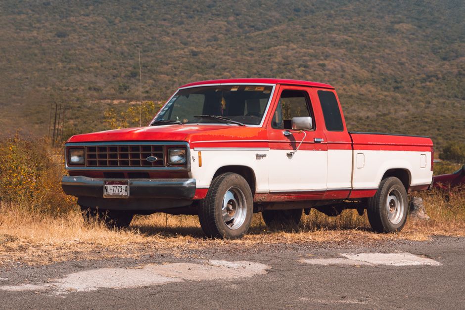 Red and white pickup truck parked on a roadside.
