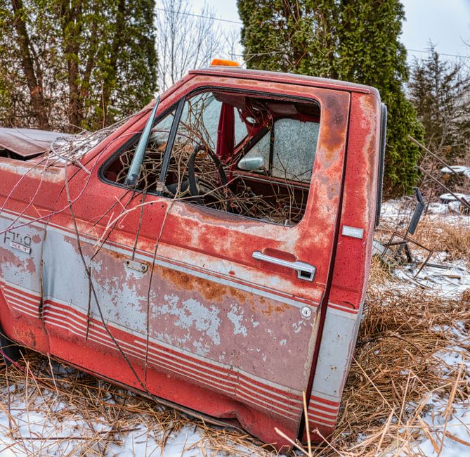 Old rusty truck sitting in an open field.